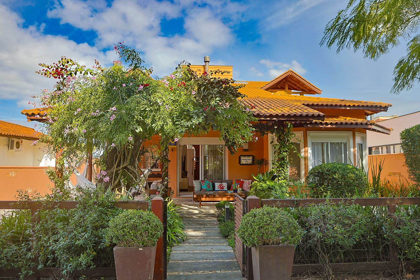 Fachada em terracota com buganvília florida e entrada ajardinada