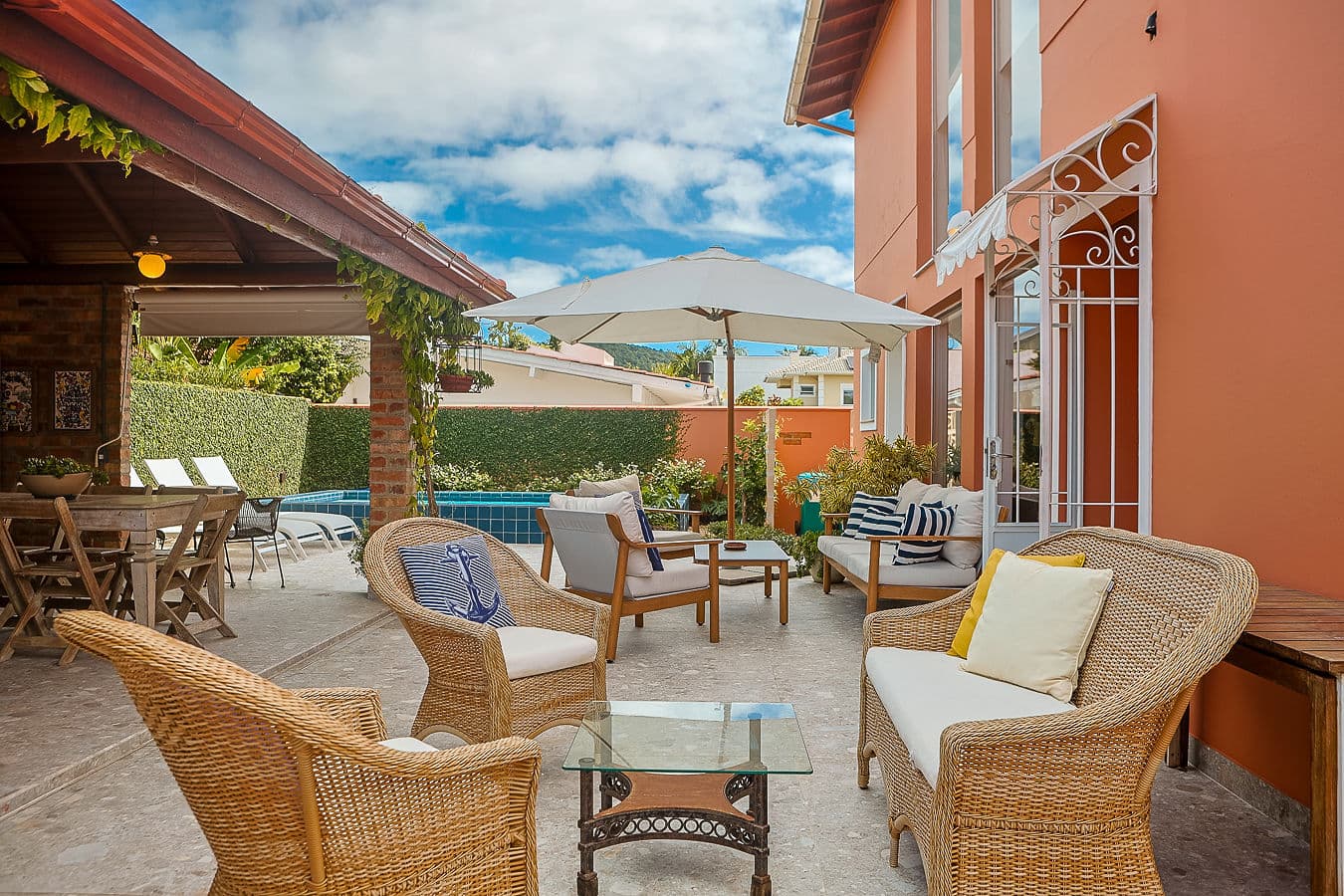 Lounge de vime com guarda-sol e piscina ao fundo