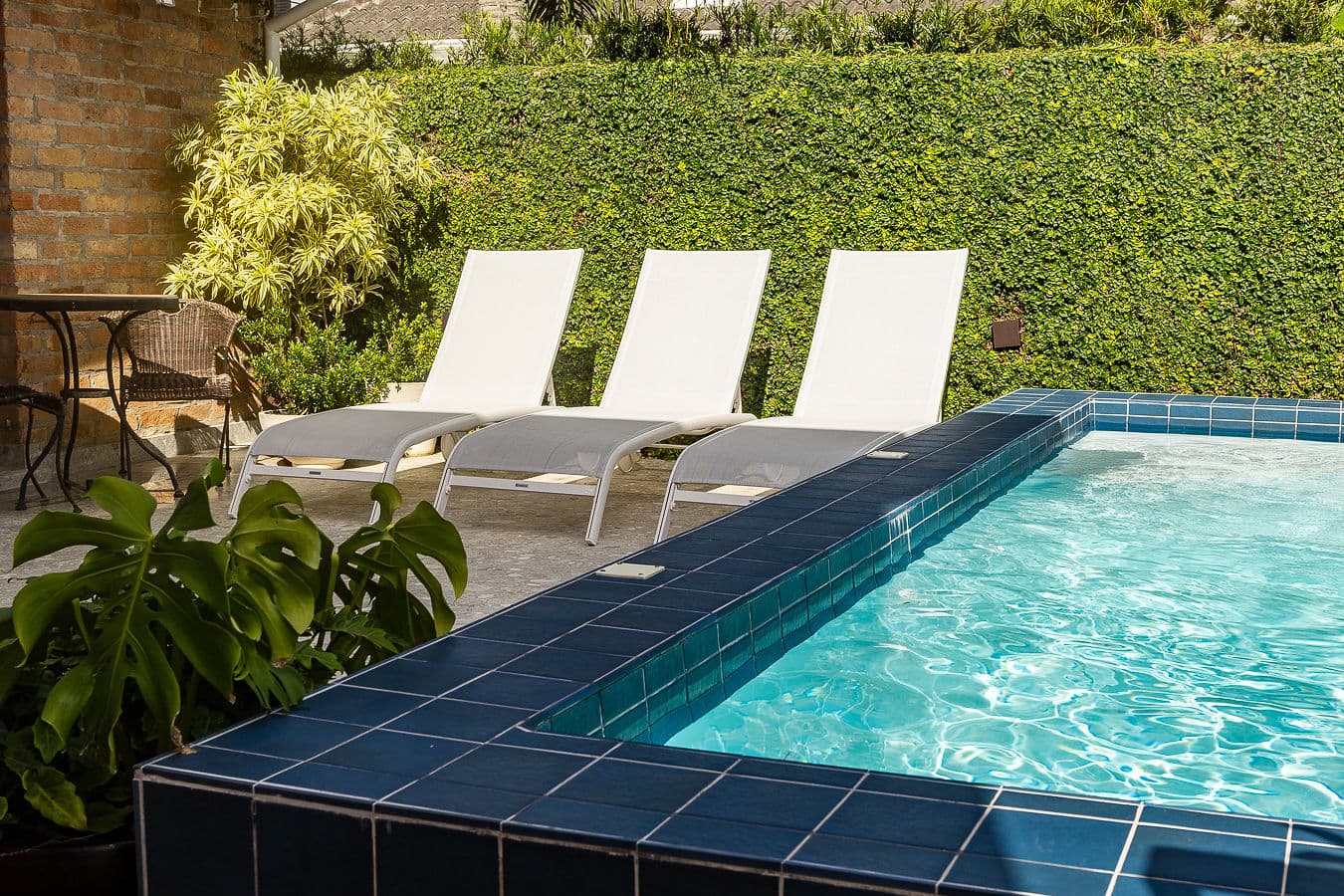 Detalhe da piscina de pastilha azul e espreguiçadeiras