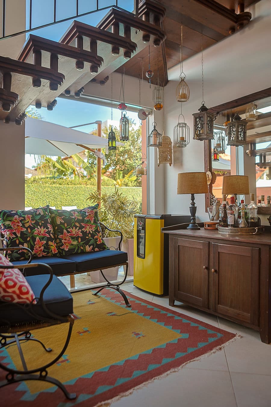 Estar com escada vazada, sofá floral e aparador bar