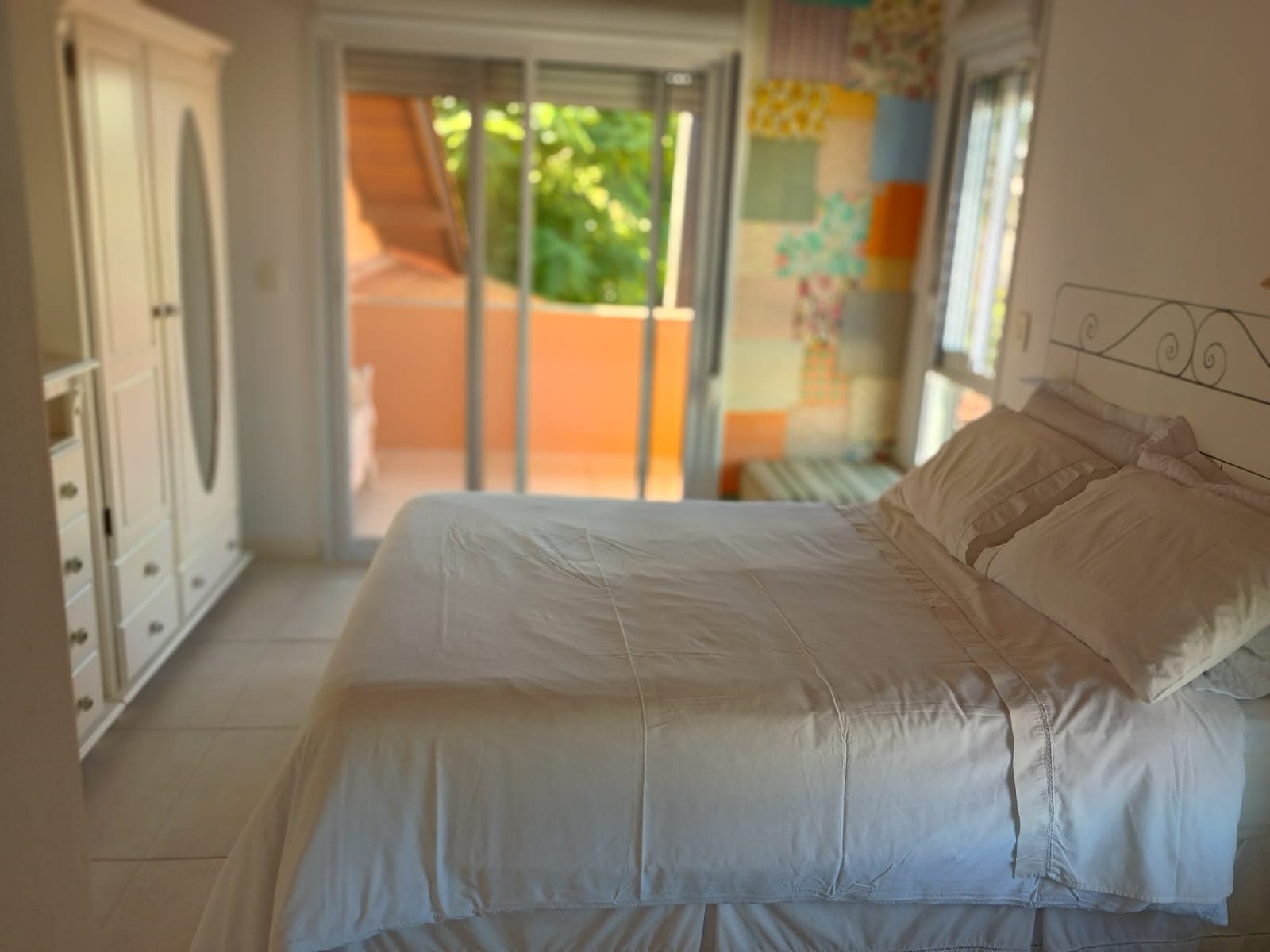 Suíte ampla com cama de casal, closet branco e varanda com vista para o jardim